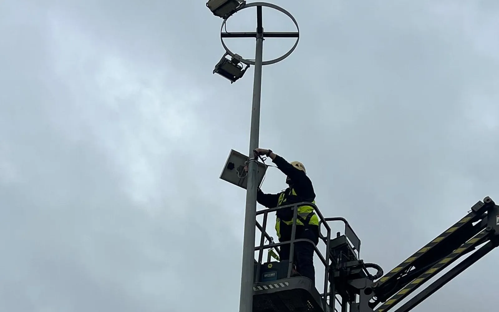 Técnico conectando una cámara con panel solar en un poste